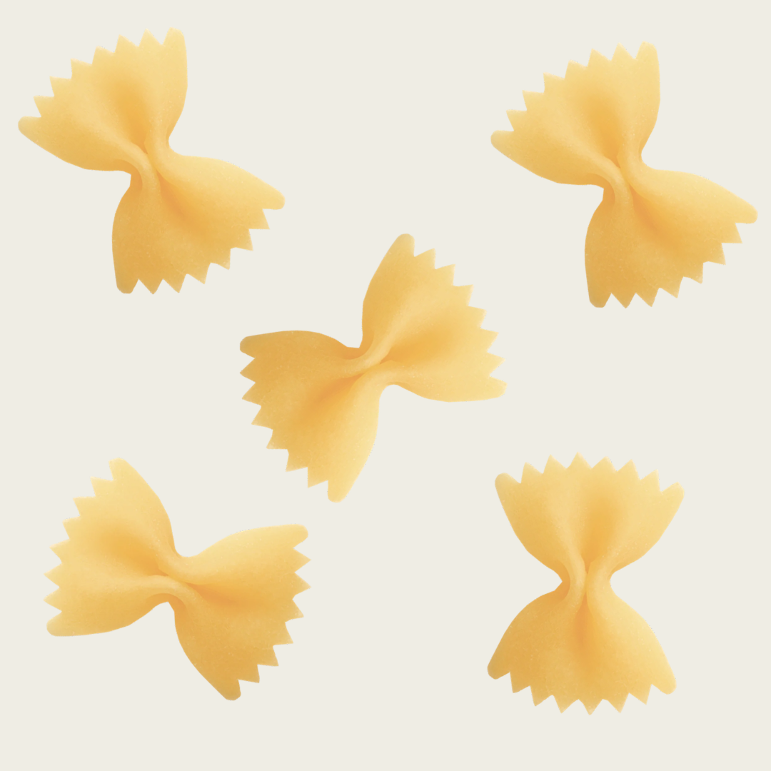 Four bow-shaped pasta pieces on a light beige background