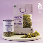 Organic Olympus Tea packaging and loose tea on a marble board with a purple background