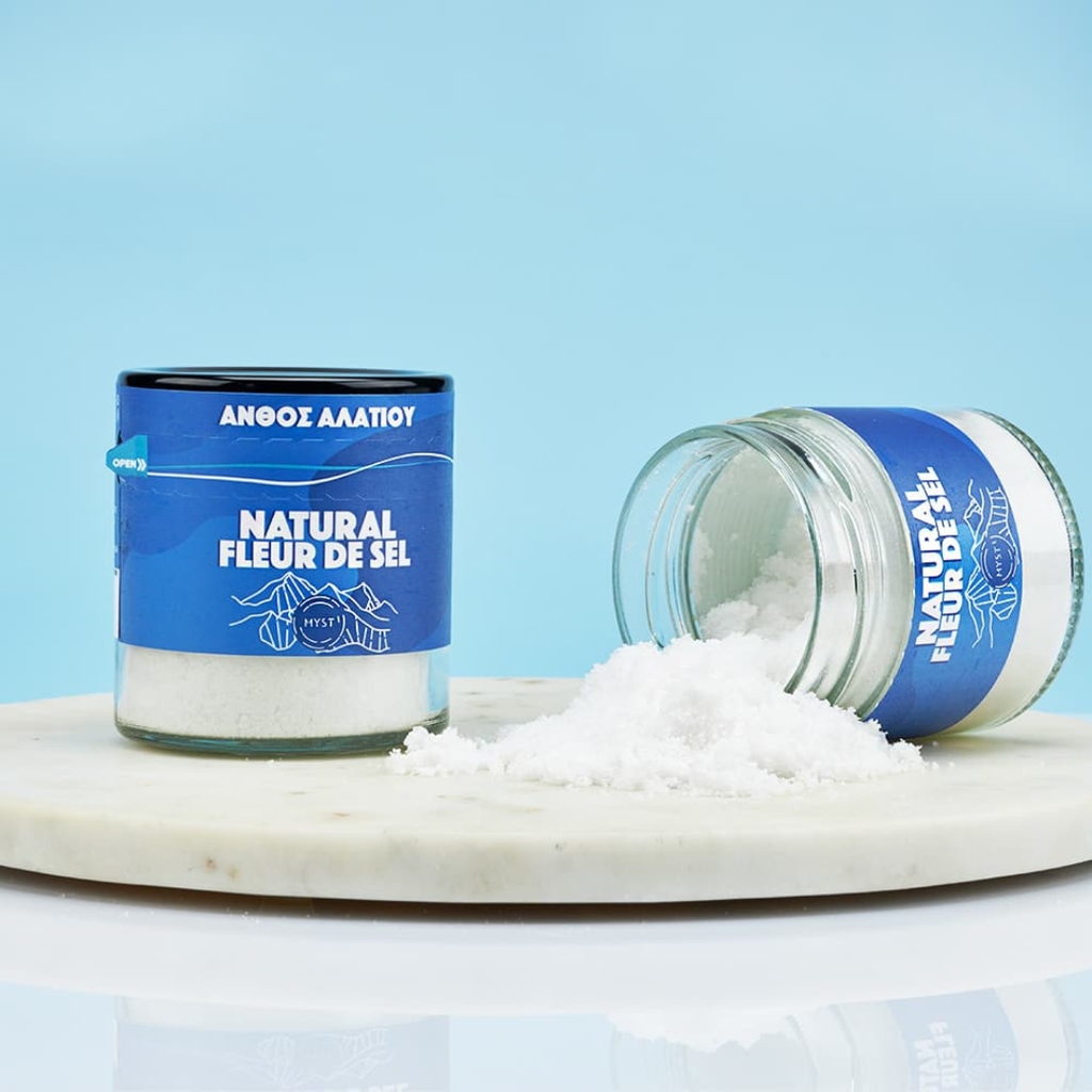 Two jars of 'Natural Fleur de Sel' on a marble surface with a blue background