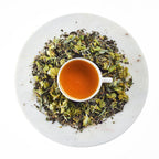 Tea cup with green tea leaves on a white plate