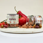 Two containers of Mediterranean Fleur de Sel seasoning on a marble board with vegetables.