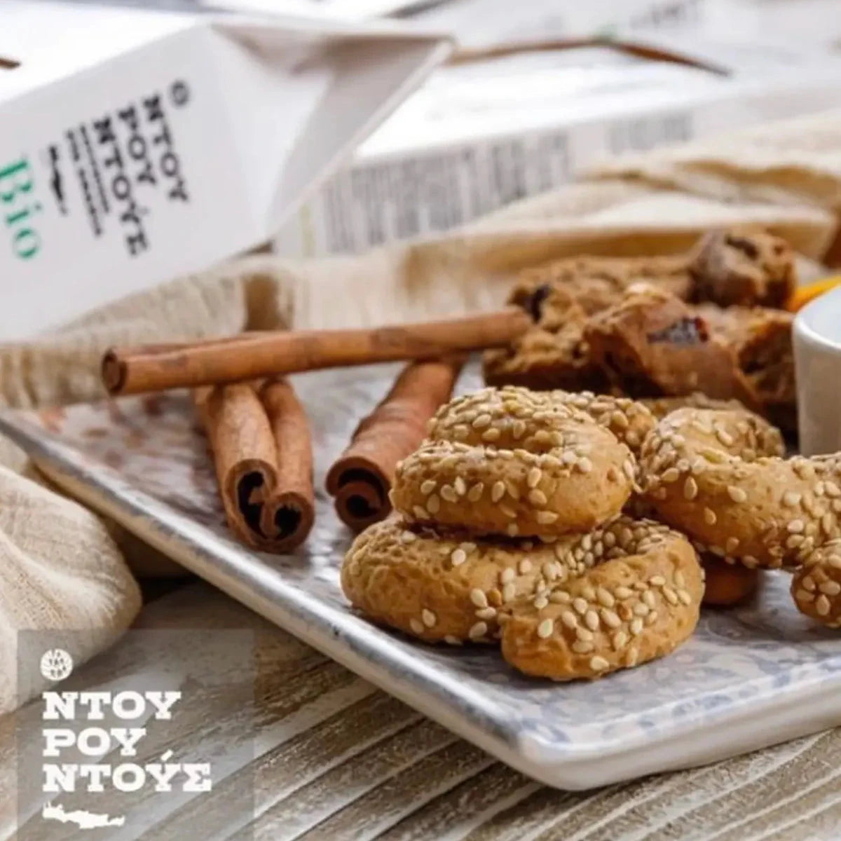 Cookies on a tray with cinnamon sticks and a branded package in the background