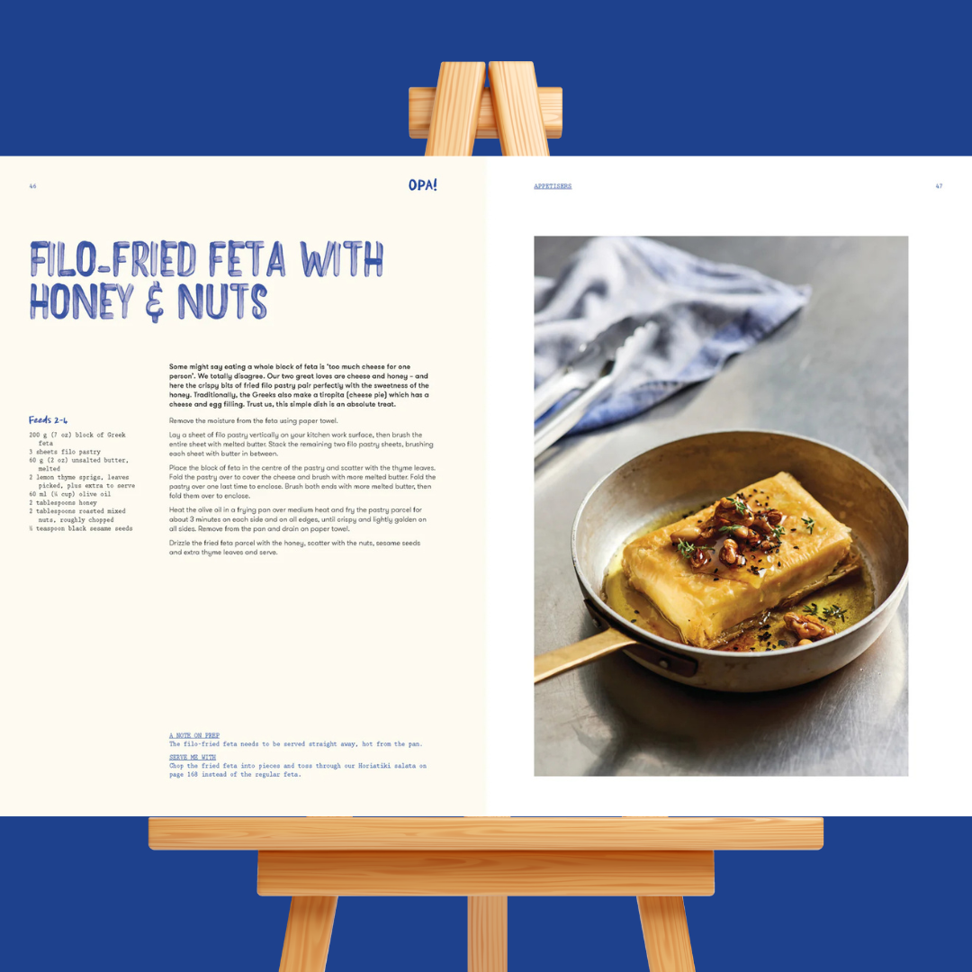 Cookbook page with filo-fried feta dish on a wooden stand against a blue background