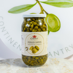 Jar of pickled capers with a label on a marble surface, with green leaves in the background.