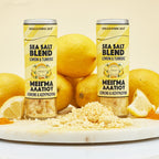 Two cans of sea salt blend with lemon and turmeric on a white surface with lemons around.