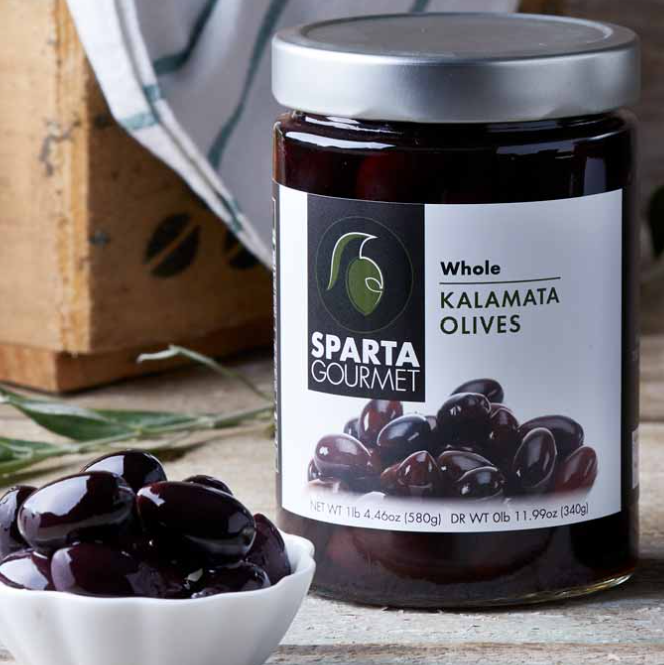 Jar of Sparta Gourmet Kalamata Olives with a bowl of olives on a wooden surface.