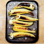 Roasted yellow bell peppers with char marks on a baking tray.