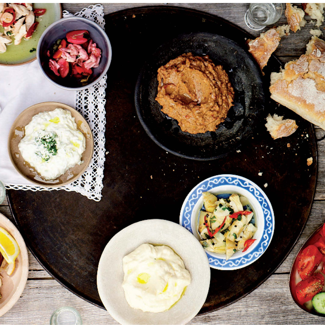 Assorted dips and spreads on a wooden board with a rustic background