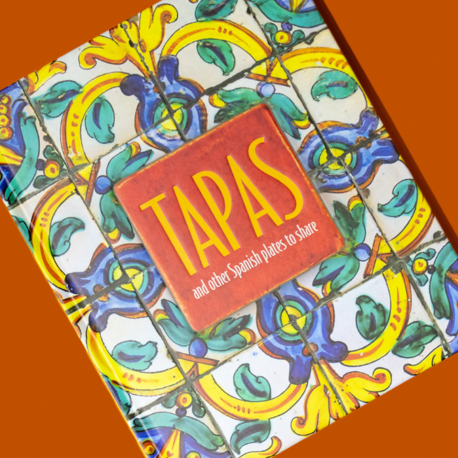 Book titled 'Tapas' with decorative cover on an orange background