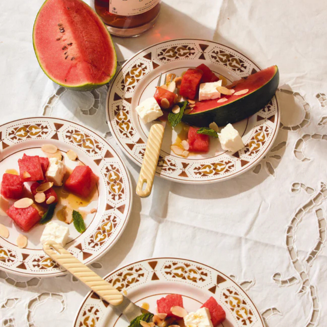 Plates of watermelon salad with feta cheese on a decorative tablecloth.