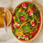Salad with watermelon, oranges, and greens on a plate with a side of dressing.