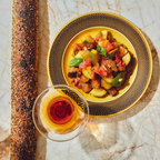 Plated vegetable dish with a glass of red wine on a marble surface
