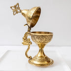 Decorative gold goblet with intricate designs on a white background