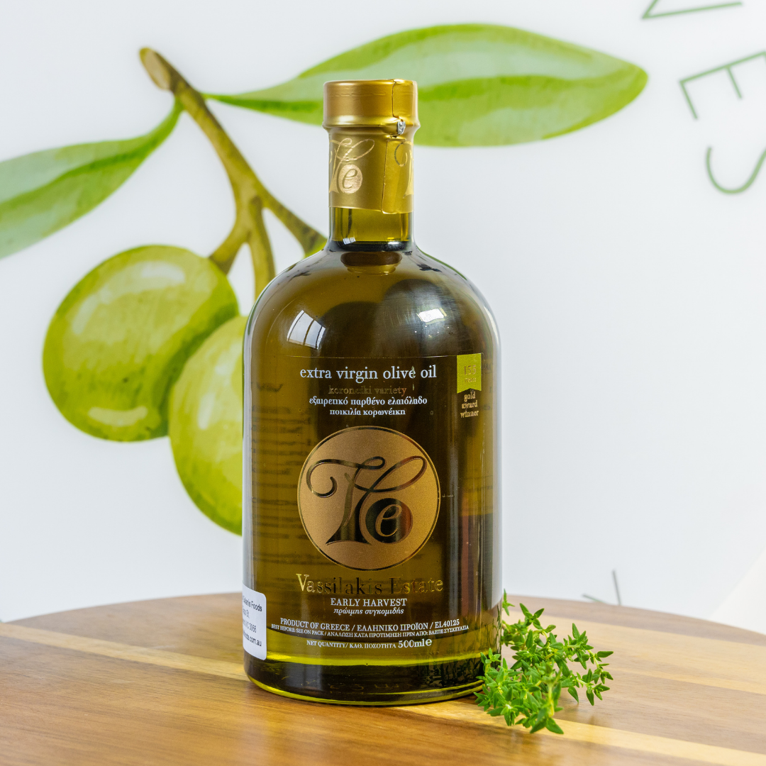 Bottle of extra virgin olive oil on a wooden surface with green leaves in the background