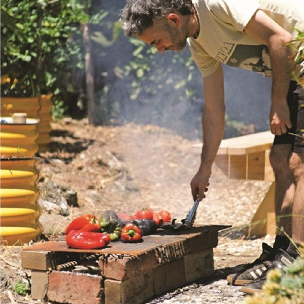 Person roasting vegetables on a grill outdoors