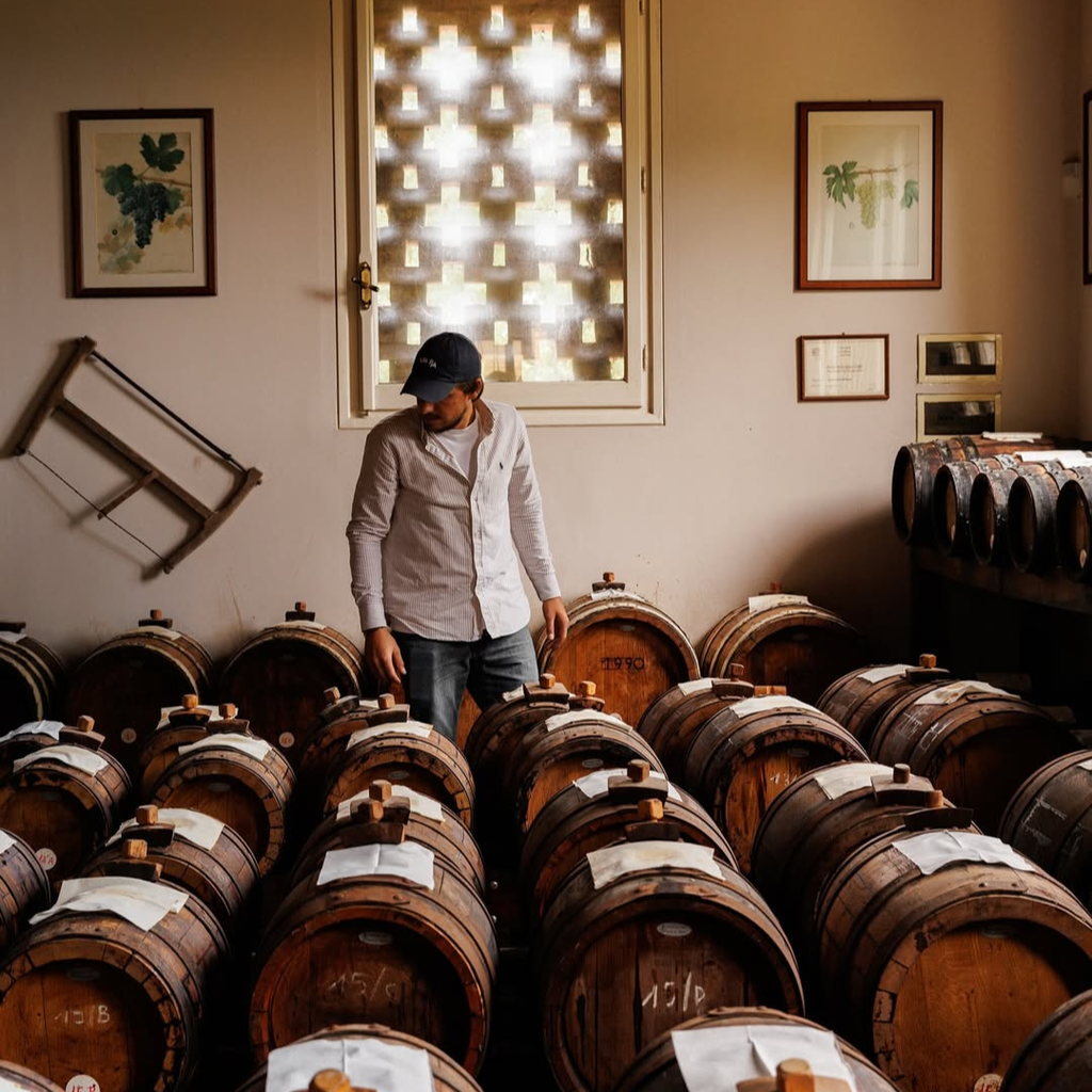 Person standing among rows of wooden barrels in a storage room.