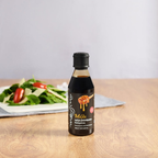 Bottle of Mel honey on a wooden table with a salad in the background