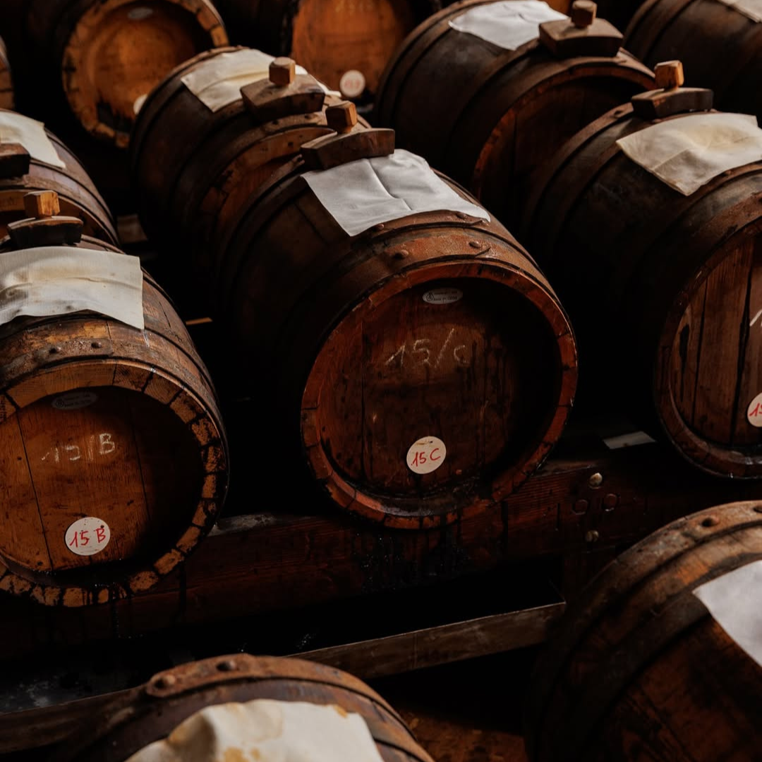 Stack of wooden barrels with visible labels in a storage room.