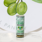 Sea salt blend container with basil and garlic flavor on a white surface with green grapes in the background.