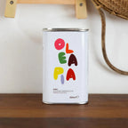 White canister with colorful 'Olea Pa' branding on a wooden surface.