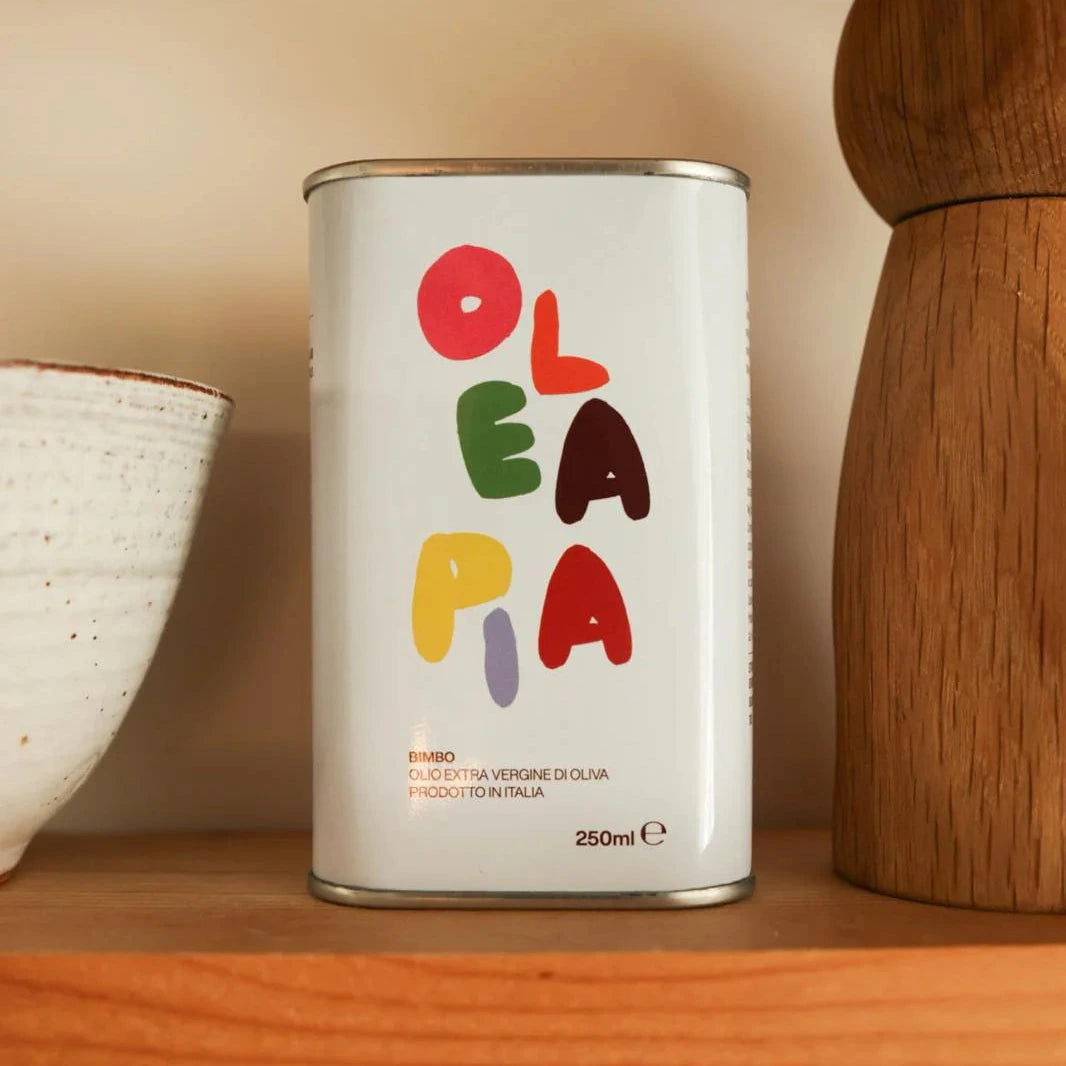 Canister with 'Olea Pa' branding on a wooden shelf with a wooden pepper grinder and ceramic bowl.