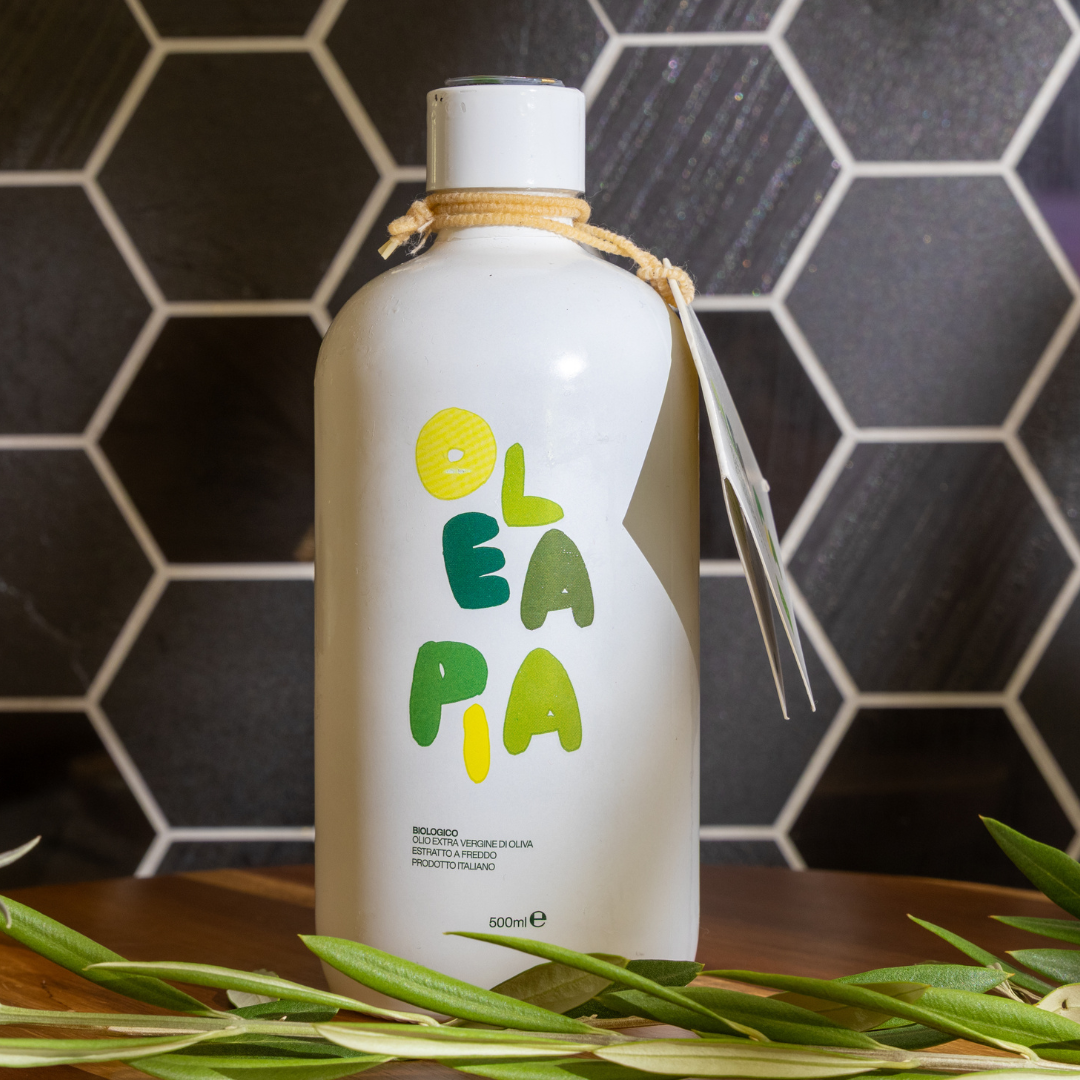 White bottle with 'Olea Pa' branding on a dark tiled wall background