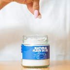 Jar of 'Natural Fleur de Sel' salt with a hand holding it on a blurred background