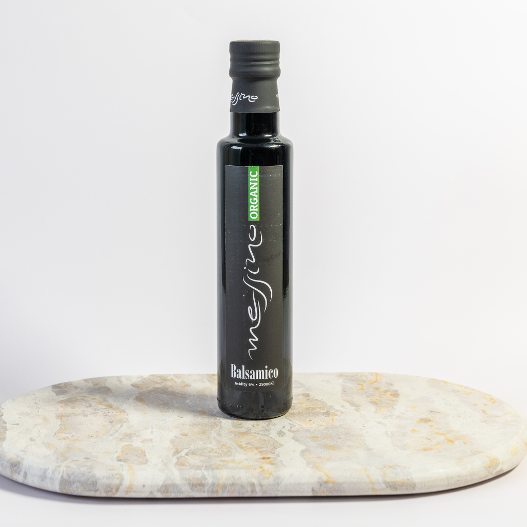 Bottle of Messina Organic Balsamic vinegar on a marble surface with a white background