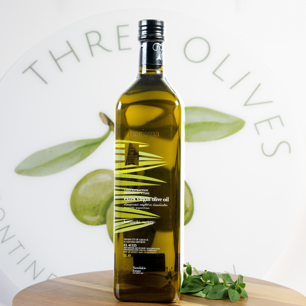 Bottle of olive oil with olive leaves on a white background, featuring the brand 'Three Olives'.