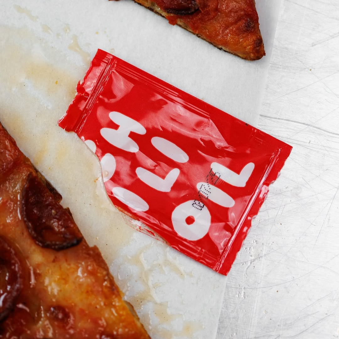 Red packet with white text on a white surface with pizza slices