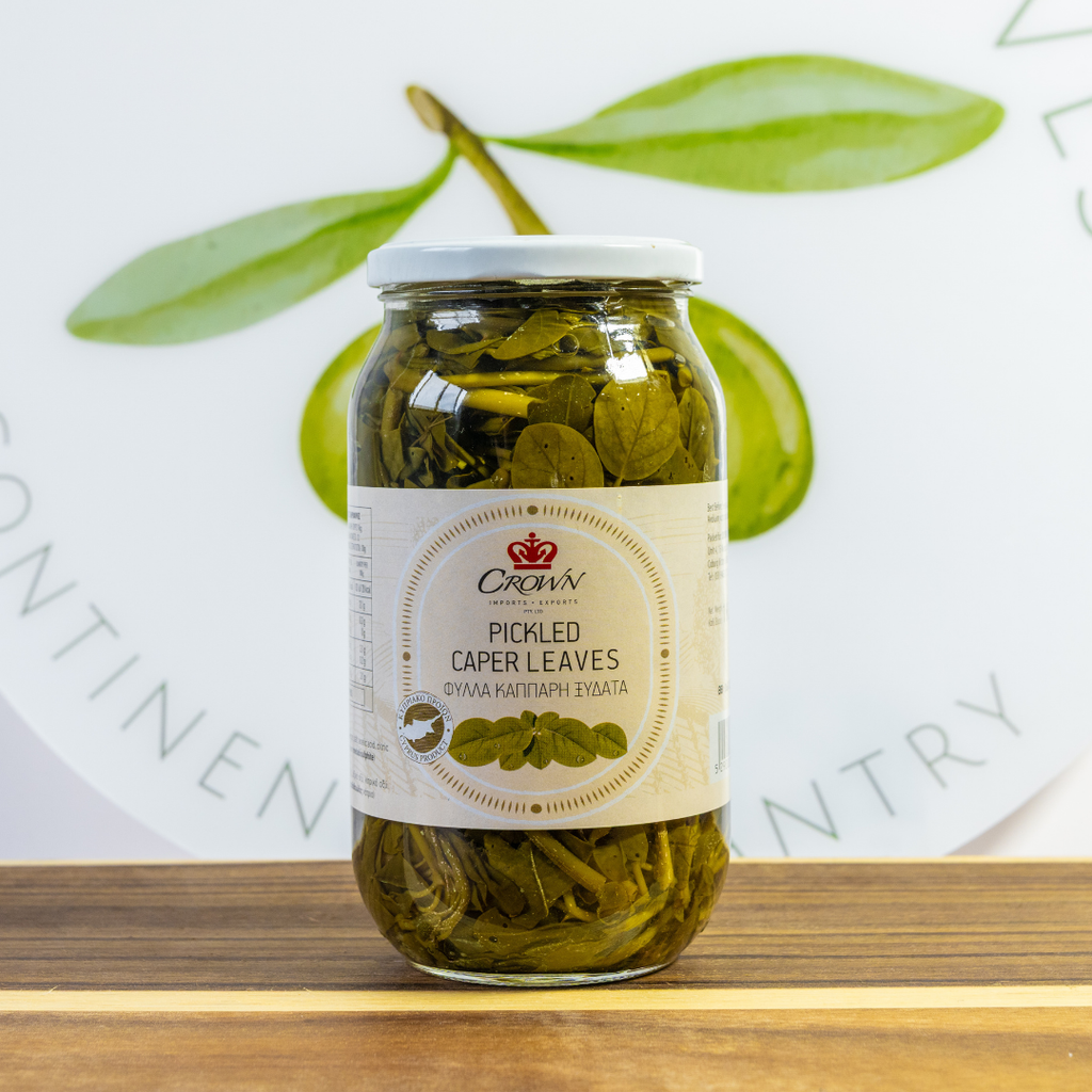 Jar of pickled caper leaves with a visible label on a wooden surface.