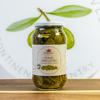 Jar of pickled caper leaves with a visible label on a wooden surface.
