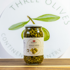 Jar of pickled capers with a visible brand label on a wooden surface.