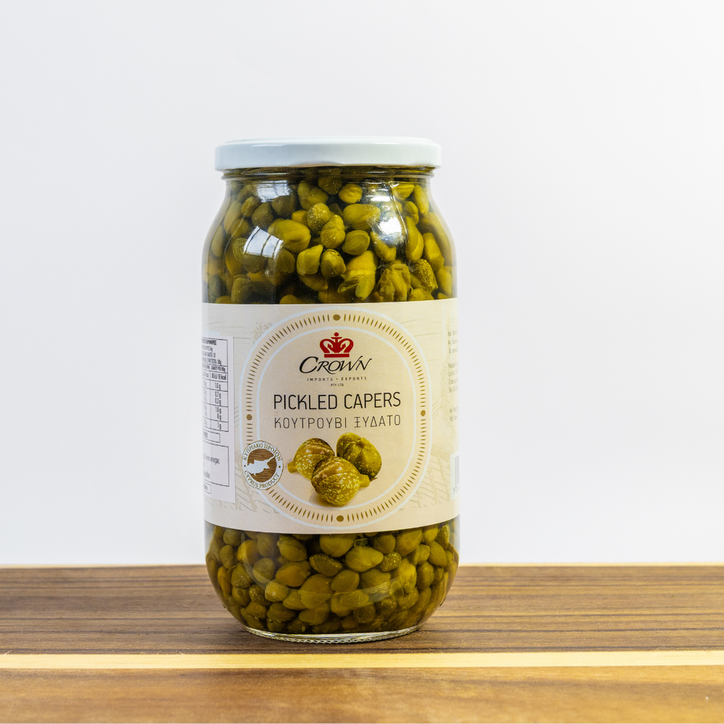 Jar of pickled capers with a visible brand label on a wooden surface.