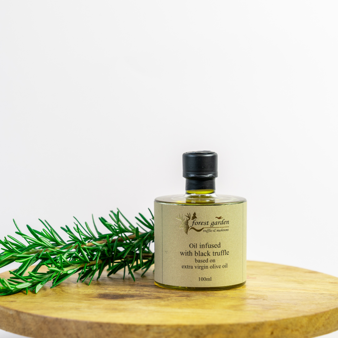 Bottle of oil infused with black truffle on a wooden surface with a white background