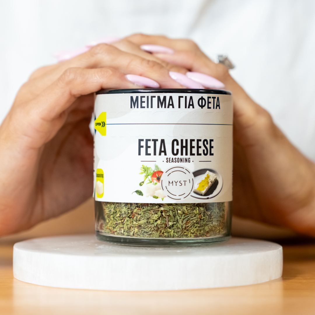 Jar of feta cheese seasoning held by a person on a white surface
