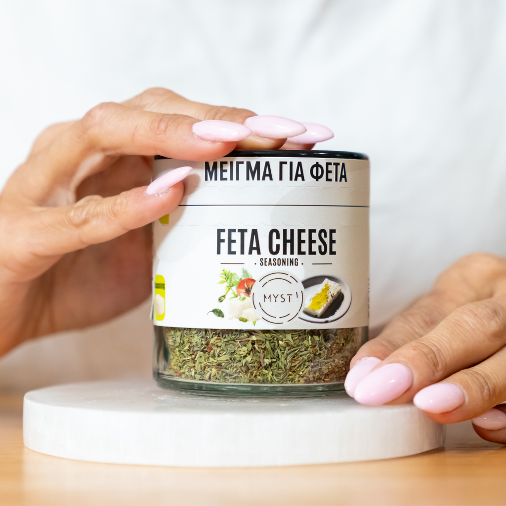 Jar of feta cheese seasoning held by a person with a white background