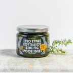 Jar of Kymi Fig Spread on a marble surface with a sprig of thyme.