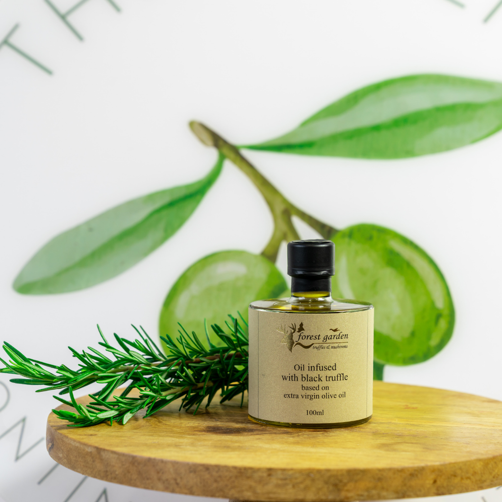 Bottle of Forest Garden olive oil with green leaves on a wooden surface