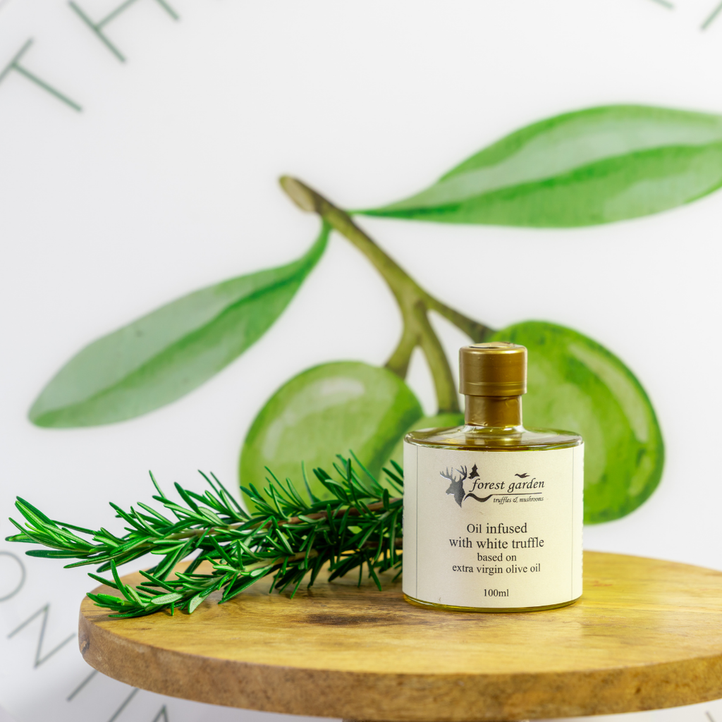 Bottle of Forest Garden olive oil with green leaves on a wooden surface