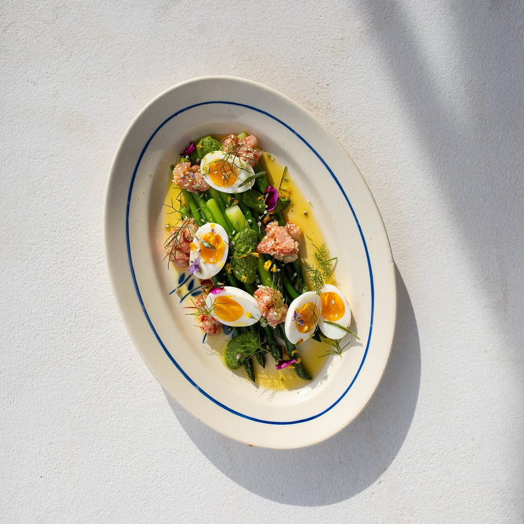 Egg salad with vegetables on a white plate with blue rim against a light background
