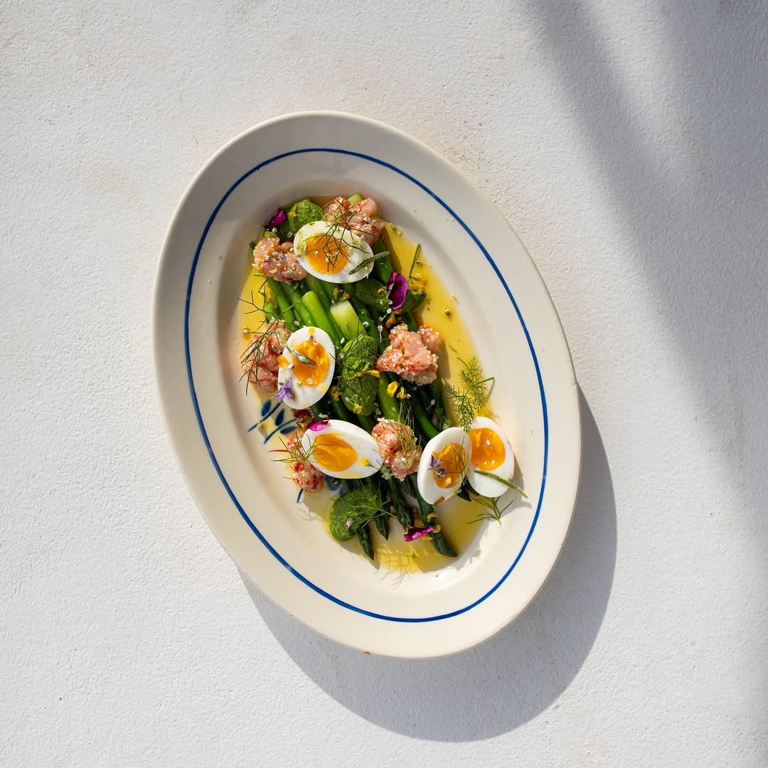 Egg salad with vegetables on a white plate with blue rim against a light background