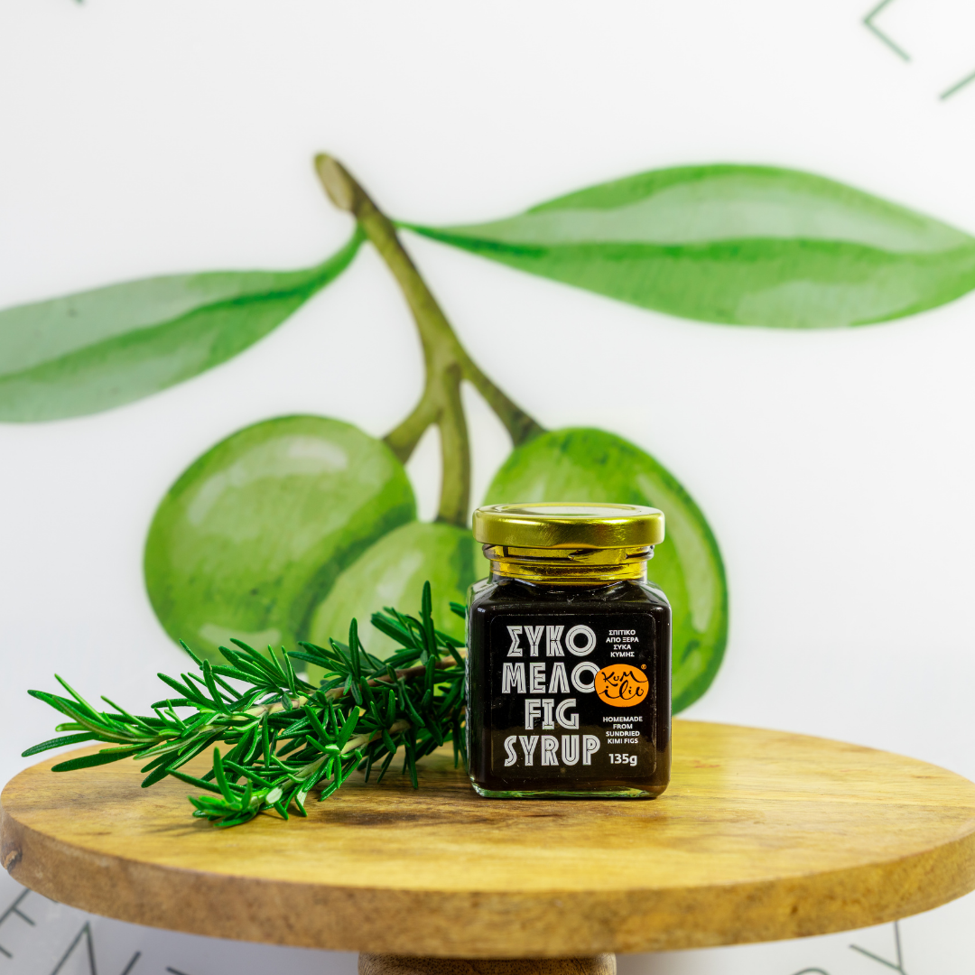 Jar of EYKO MEAO FIG SYRUP on a wooden surface with green figs and rosemary in the background.