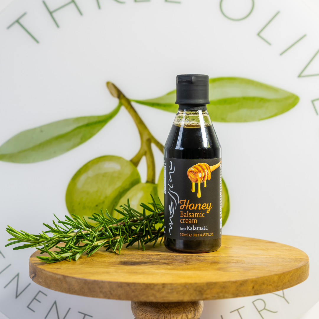 Bottle of honey balsamic cream on a wooden stand with green leaves in the background