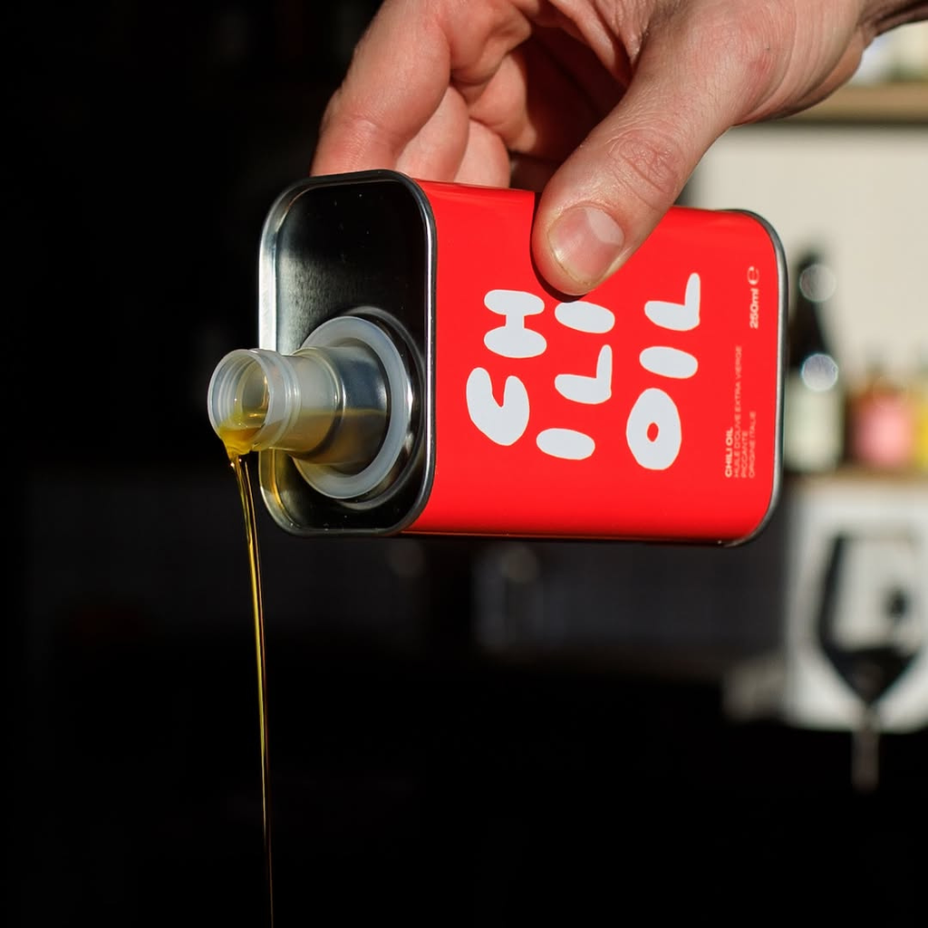 Red container with white text being poured into a clear container, blurred background