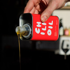 Red container with white text being poured into a clear container, blurred background