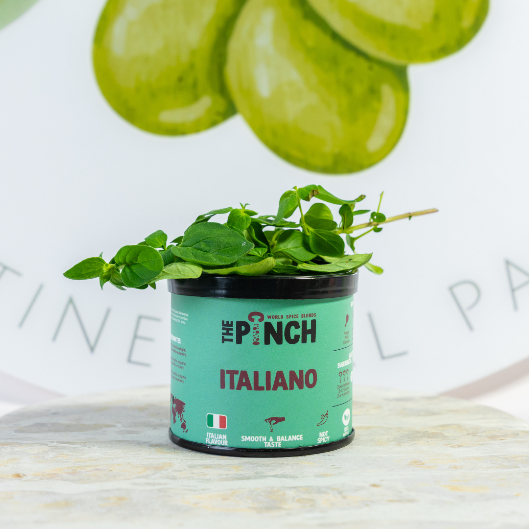Container of 'The Pinch Italiano' with fresh green herbs on a marble surface.