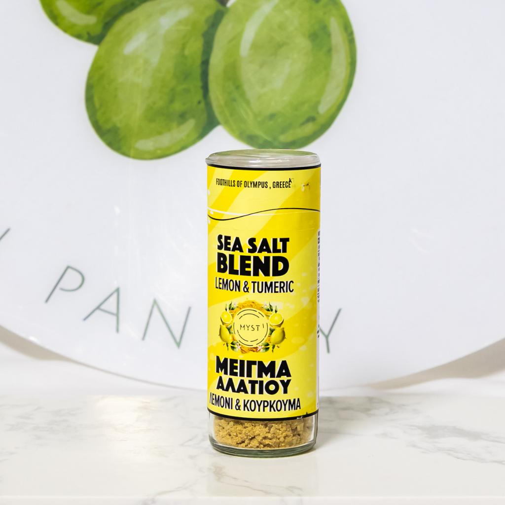 Can of sea salt blend with lemon and turmeric flavor on a marble surface with green grapes in the background.