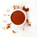 Small white bowl filled with red powder on a white background