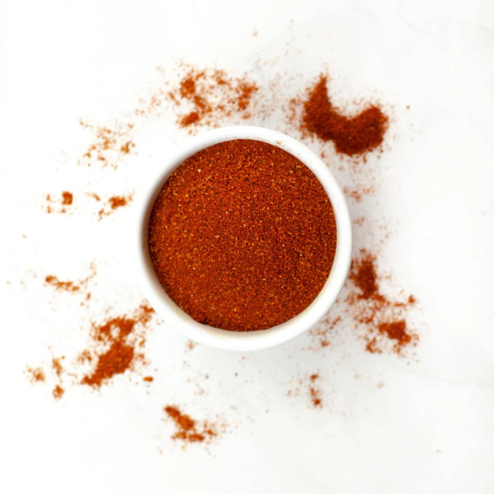 Small white bowl filled with red powder on a white background